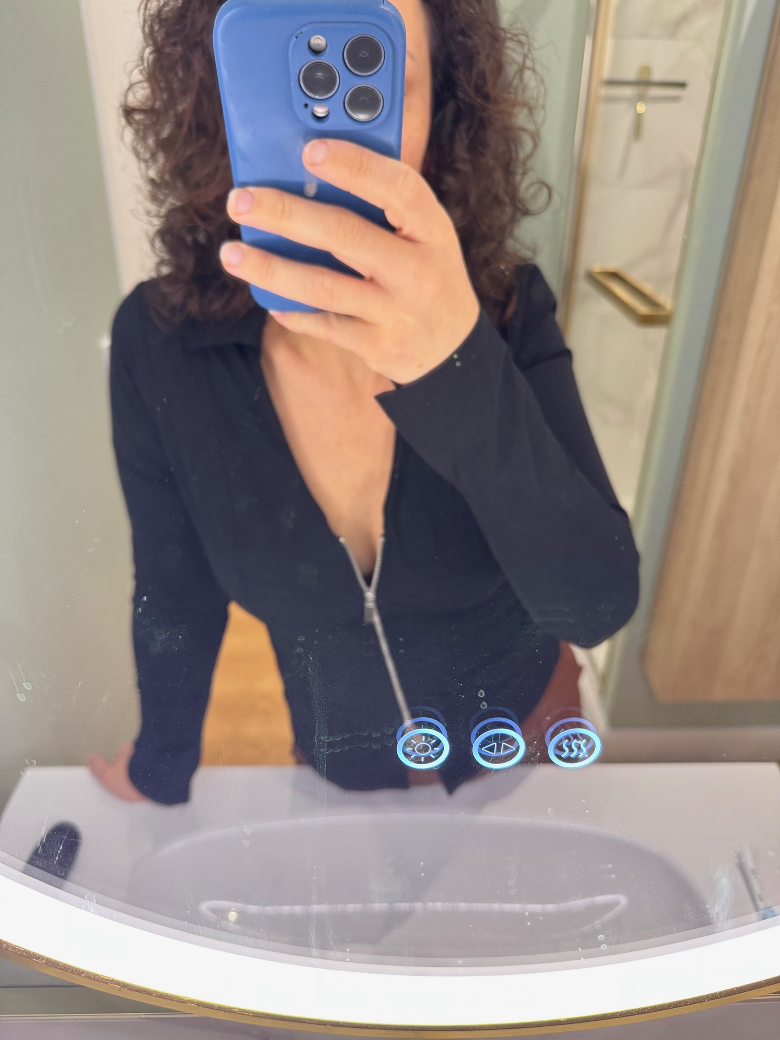 Klara tar en spegelselfie i en svart tröja med dragkedja, mobilen framför ansiktet